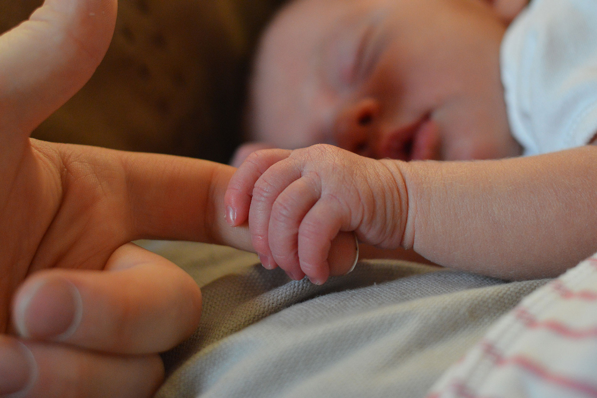 La manina di un neonato che stringe il dito di un adulto